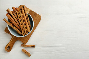 Aromatic cinnamon sticks on white wooden table, flat lay. Space for text