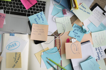 Laptop, notes and office stationery in mess on desk, top view. Overwhelmed with work