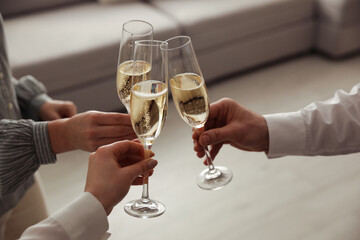 People clinking glasses with champagne at home, closeup
