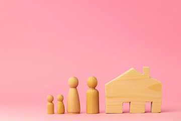 Wooden house miniature and toy people on pink background