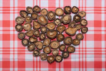 Shiitake mushroom caps are arranged in a heart shape on the table.