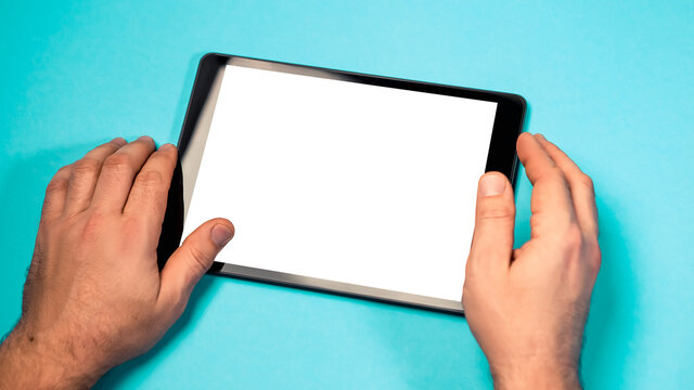 Cropped close up view mock up image man hand hold black tablet pc white blank screen isolated blue bright background. Digital modern gadget, remote distance work concept. Free empty space for text
