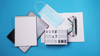 Flat lay tablet pc white notebook isolated blue background. Digital modern gadget, remote distance work concept. Face travel surgical hygienic disposable mask. Work at home concept.
