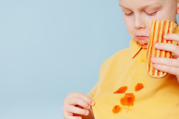  Clumsy child staining her shirt with ketchup Sauce. Child ruining her t-shirt with tomato sauce eating Hot Dog