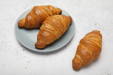 Plate with tasty croissants on stone background. French pastry.