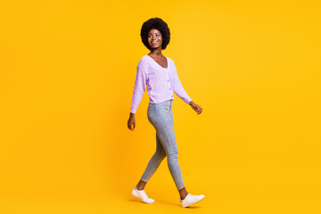 Fototapeta na wymiar Full size profile photo of positive dark skin person walking look empty space isolated on yellow color background