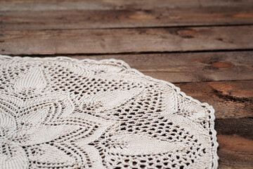 Crocheted tablecloth on an old wooden background. The subject of needlework is a knitted napkin. Vintage interior item. Wedding, Easter concept.