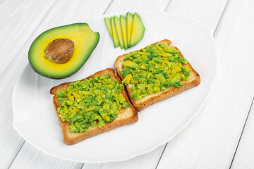 Toasts with avocado on white wood background