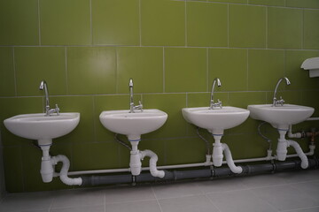 Baby low washstands on the green wall in kindergarten