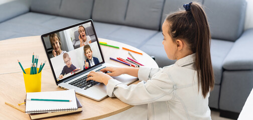 girl looking at laptop with videoconference children classmates standing on the table