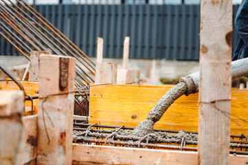 Fototapeta premium caucasian workers pouring concrete with concrete pump. Details of construction site and close up details of worker workwear