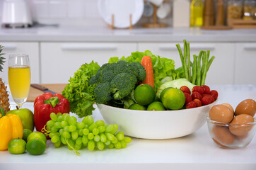 Fresh vegetables, fruits and eggs on white table in home modern kitchen.