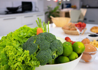 Healthy foods of fresh vegetables and eggs on white table in home kitchen.