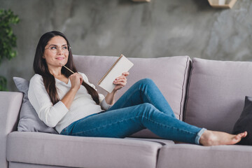Photo of minded thoughtful girl lay sofa relax look up think wear eyeglasses white pullover in living room home indoors © deagreez