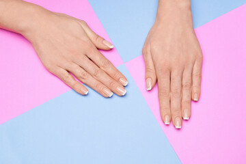 Naklejka premium Beautiful Female Hands with French manicure over colorful paper background