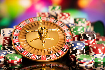 Casino theme.  Roulette wheel, poker chips and dice on  colorful bokeh background.