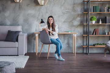 Photo of business lady sit chair look camera wear eyewear white sweater jeans footwear in living...