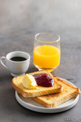 Crusty toasts with butter and jam ? cup of coffee and orange juice. Popular snack for breakfast in many countries.