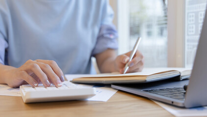 Head of accounting is recording the company's financial growth statistics using graphs as a reference for reviewing and analyzing the results, Taking notes and analyzing data graphs in office.