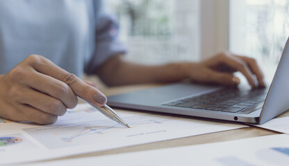 Finance workers are reviewing the company's financial data on a laptop and using smartphones to communicate or chat with the team at social distances, Working during the virus outbreak.