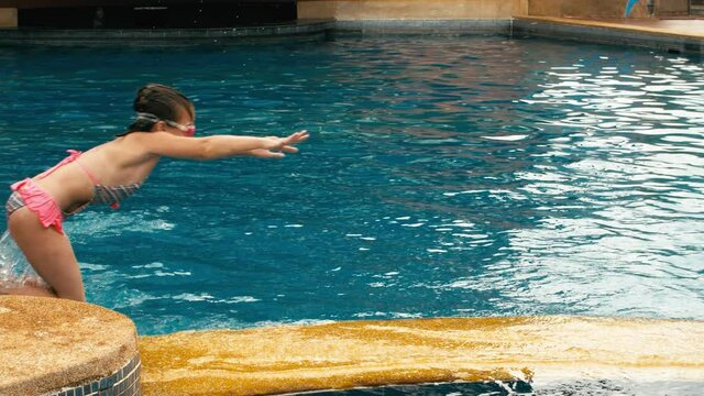 The father with little daughter have fun in the pool. Dad plays with the child. The family enjoy summer vacation in a swimming pool jumping, spinning, splash water. Slow motion.