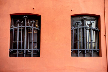 old window with shutters,  terracotta wall with windows in forged lattices, house exterior, building fragments, city architecture