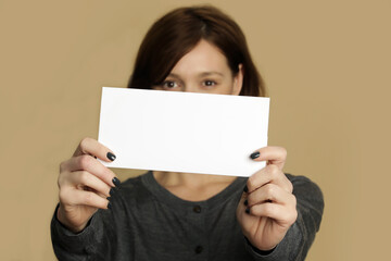 Fototapeta na wymiar Portrait of young woman holds blank white paper tag. 