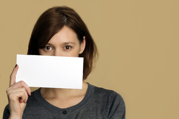 Portrait of young woman holds blank white paper tag.
