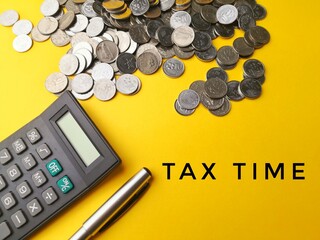 Coins, Calculator and pen isolated over yellow background written TAX TIME