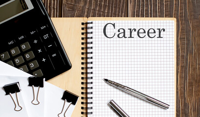 Notepad with text CAREER on the wooden background with clips, pen and calculator