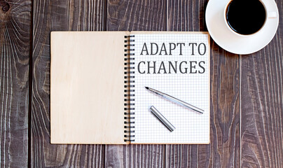 Word Writing Text ADAPT TO CHANGES with pen and cofee. business concept on wooden background