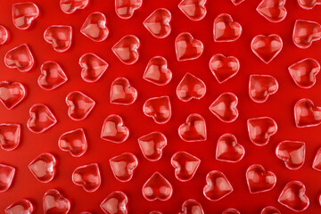 Red background with transparent glossy glass hearts. Concept of love and St. Valentine's day