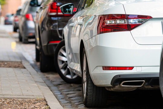rows of cars parked along the roadside in crowded city