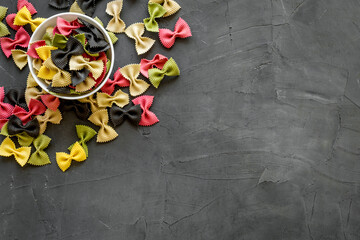 Fototapeta na wymiar Top view of coloured farfalle pasta in bowl
