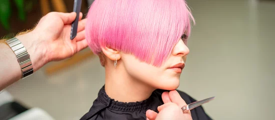 Fotobehang Male hairdresser makes short pink hairstyle for a young caucasian woman in a beauty salon © okskukuruza