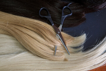 hair extensions and scissors on a dark background. Hair Care Concept. 