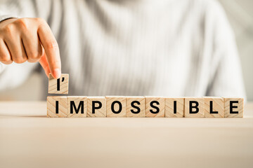 hand putting cube wooden with text impossible to i'mpossible, self development , motivate, change...