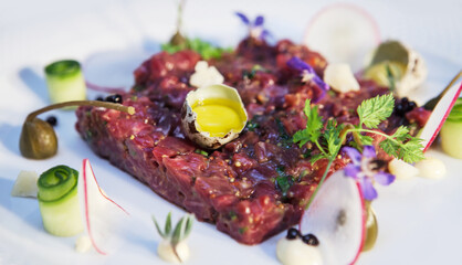 Fresh beef tartare with capers quail egg on white plate. Healthy gourmet French food made of raw meat. Close up. Selective focus.