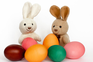 a couple of white plush bunny toys with painted easter eggs isolated on white background, pastel colors, love concept