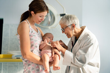 Obraz premium Mother holding baby for pediatrician doctor to examine