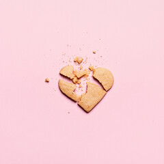 Broken heart cookies on pink background. Unrequited love and cracked relationship concept