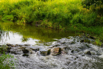 River flow over rocks in summer day. Waves of the river flow. Relaxing nature landscape scenics