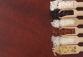 Assortment of rice in wooden scoops on table with copy space.