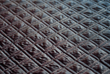 Grey quilted fabric background. Double machine stitching. Drawing in form of squares.
