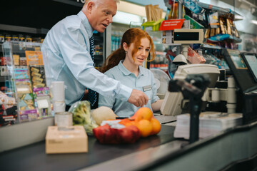 Manager teaching new employee at supermarket