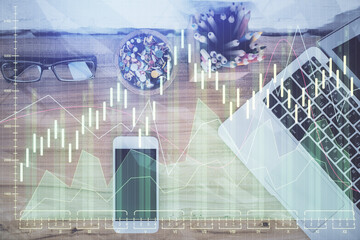 Double exposure of financial graph hologram over desktop with phone. Top view. Mobile trade platform concept.