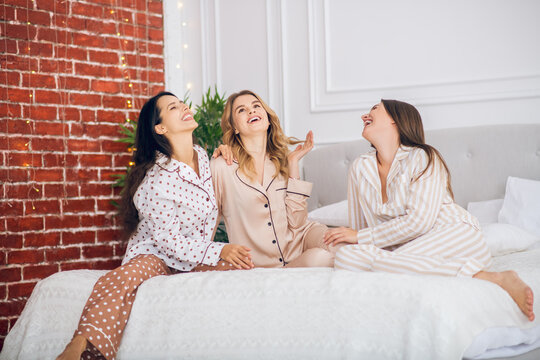 Three pretty girls in pajamas sitting on a bed
