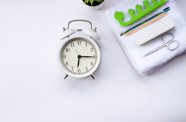 a white alarm clock and a green potted plant on a light background. White, terry towel with buff,...