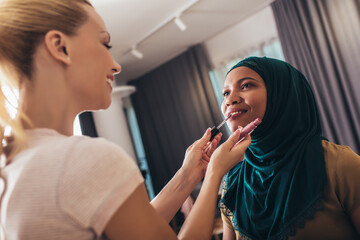 A make-up artist makes up a Muslim woman at home.