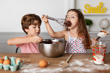Young siblings baking chocolate cake at kitchen table